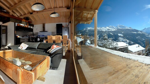 A modern interior with a wooden ceiling, a glass dining table, and a view of snow-covered mountains. - B&B - La Case A Kio Bourg-St-Maurice Les Arcs (Les Chapelles)