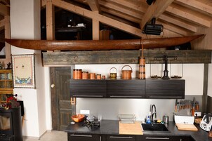 Una cocina con una canoa de madera suspendida sobre la encimera, una encimera negra y diferentes utensilios y electrodomésticos de cocina.