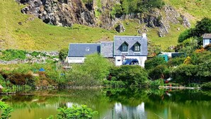 Una propiedad frente al lago con una casa de fachada de piedra y techo inclinado.