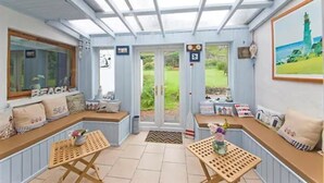 Una habitación acogedora con un gran ventanal, un banco y una mesa.