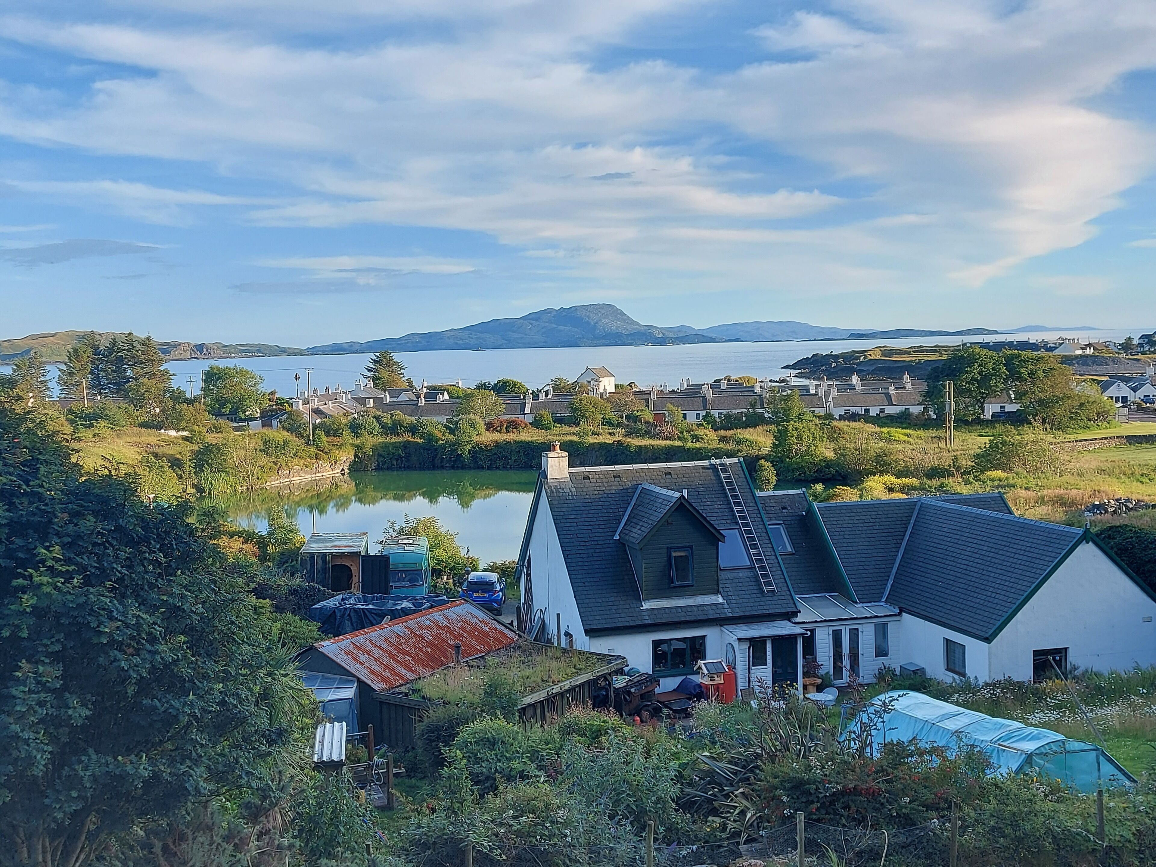 A residential area with houses, a pond, and a mountain in the background.