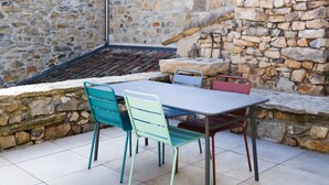 An outdoor patio with a stone wall, a tiled floor, and a table with chairs. - La Grange 1832 - 10 mins from Aubenas (Saint-Étienne-de-Boulogne)