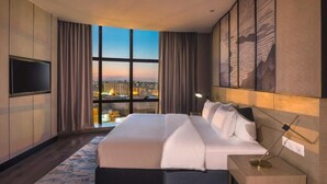 Une chambre d’hôtel moderne dotée d’un grand lit, d’une télévision et offrant une vue sur la ville grâce à de grandes fenêtres.