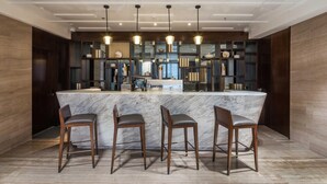 Une cuisine moderne dotée d’un îlot en marbre, de tabourets de bar, de luminaires suspendus et d’une bibliothèque intégrée.