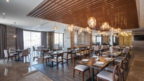Un espace de restauration moderne avec des lambris en bois au plafond, des luminaires suspendus et un plancher poli.