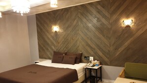 Habitació d'hotel amb llit, taulell de nit i una taula petita amb una cadira.
