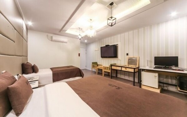 A hotel room with two beds, a desk, a chair, a television, and a minibar.