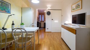 Een moderne keuken met een eethoek, een televisie en een klok aan de muur.