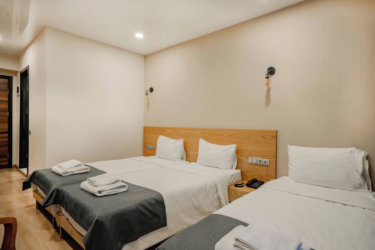 A hotel room with two beds, each with a wooden headboard, white linens, and a bedside table with a phone.