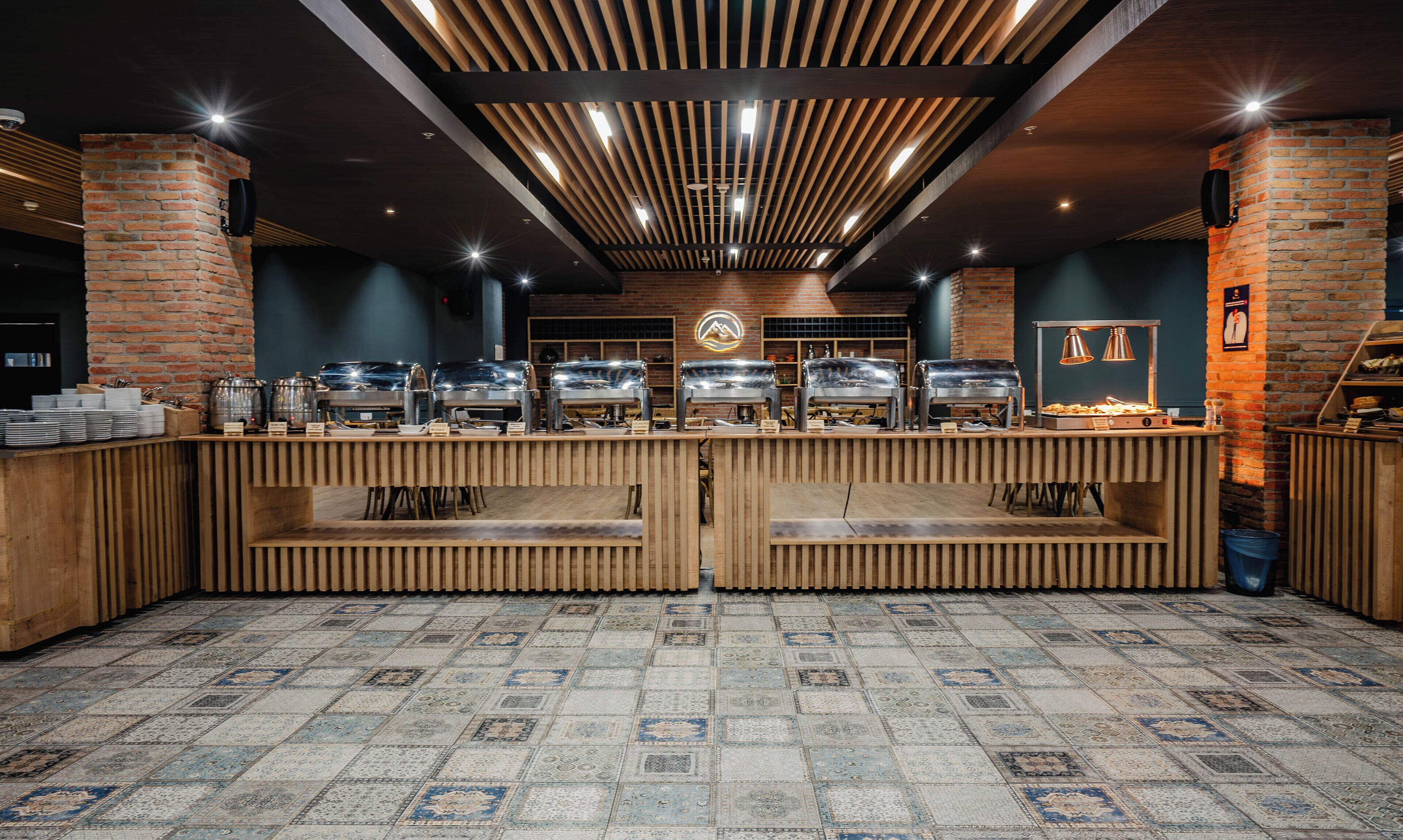 A buffet area with multiple serving stations, a brick wall, and a patterned floor.