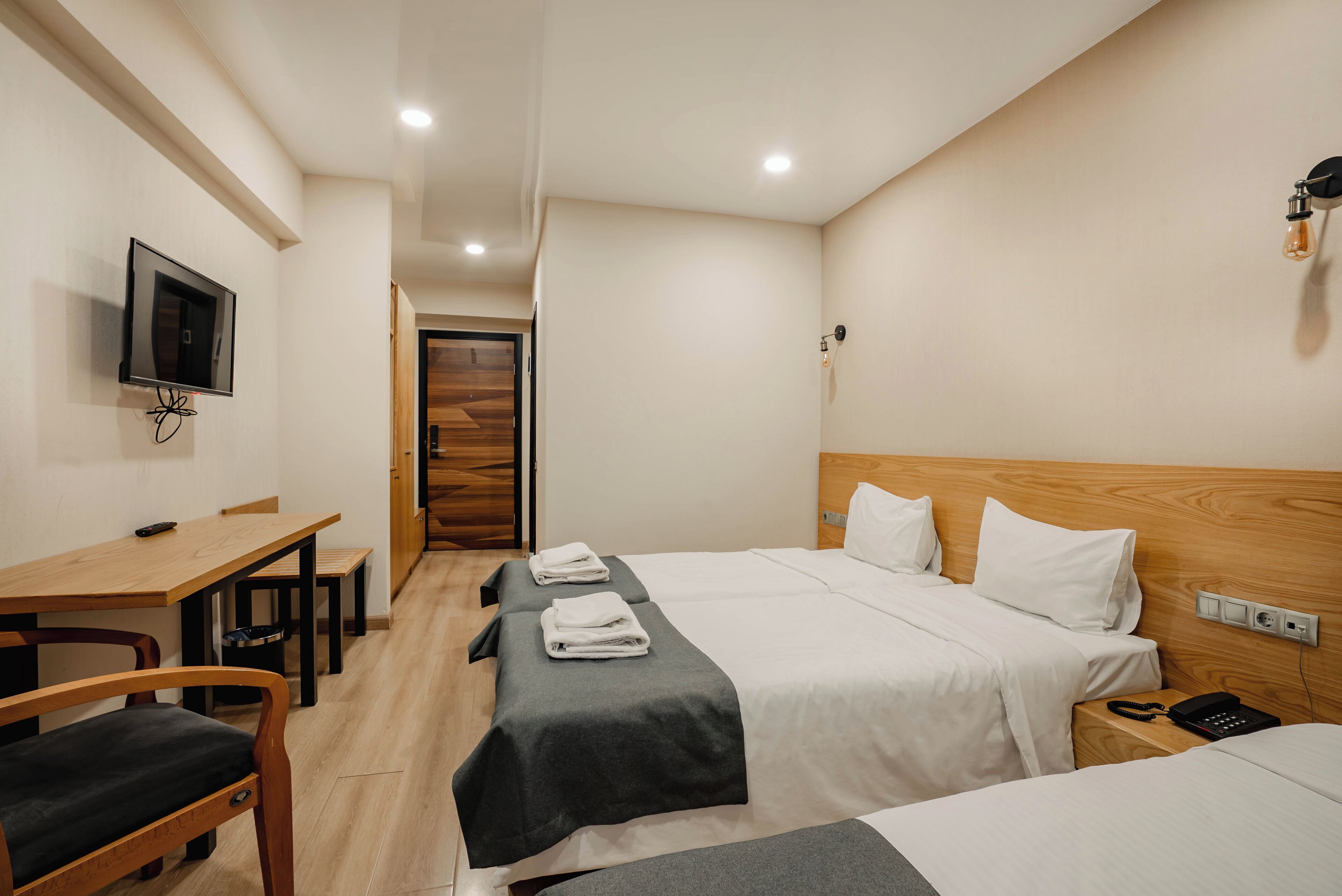 Una habitación de hotel con cama, mesitas de noche, escritorio y televisor.