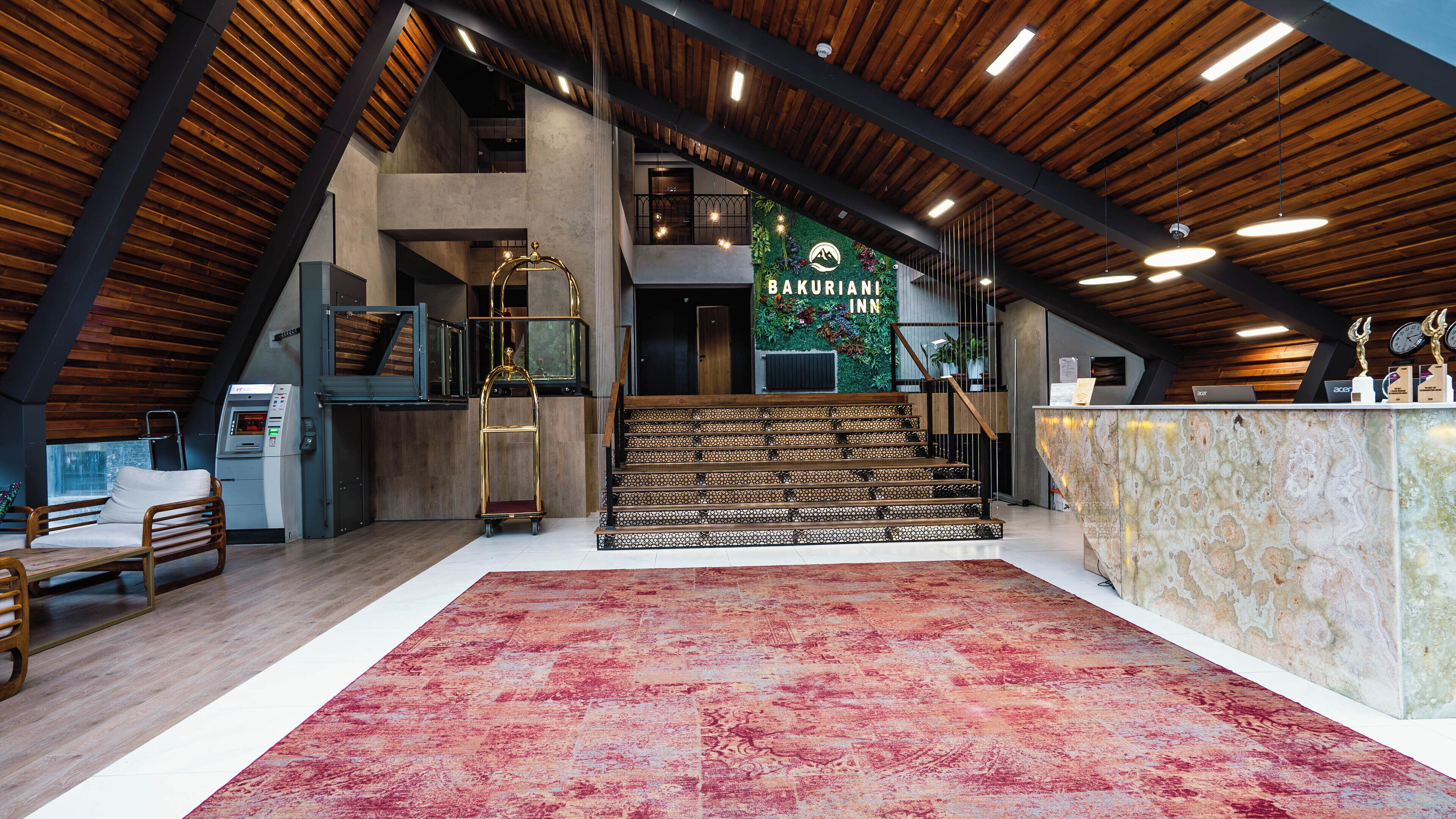 Un interior moderno con techo de madera, un mostrador de recepción, una escalera y una zona de estar.
