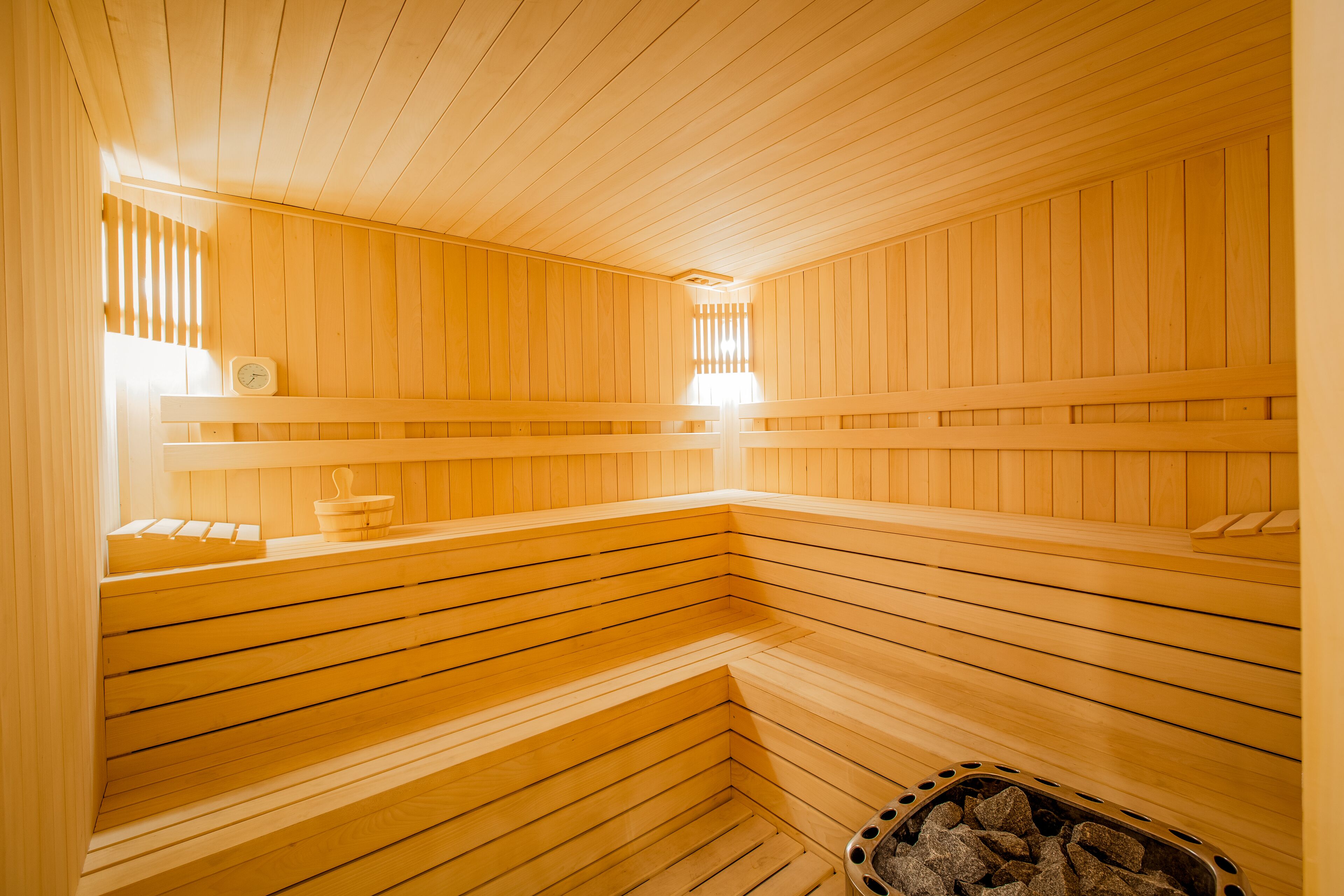 Un sauna avec des bancs en bois et un bassin en pierre.