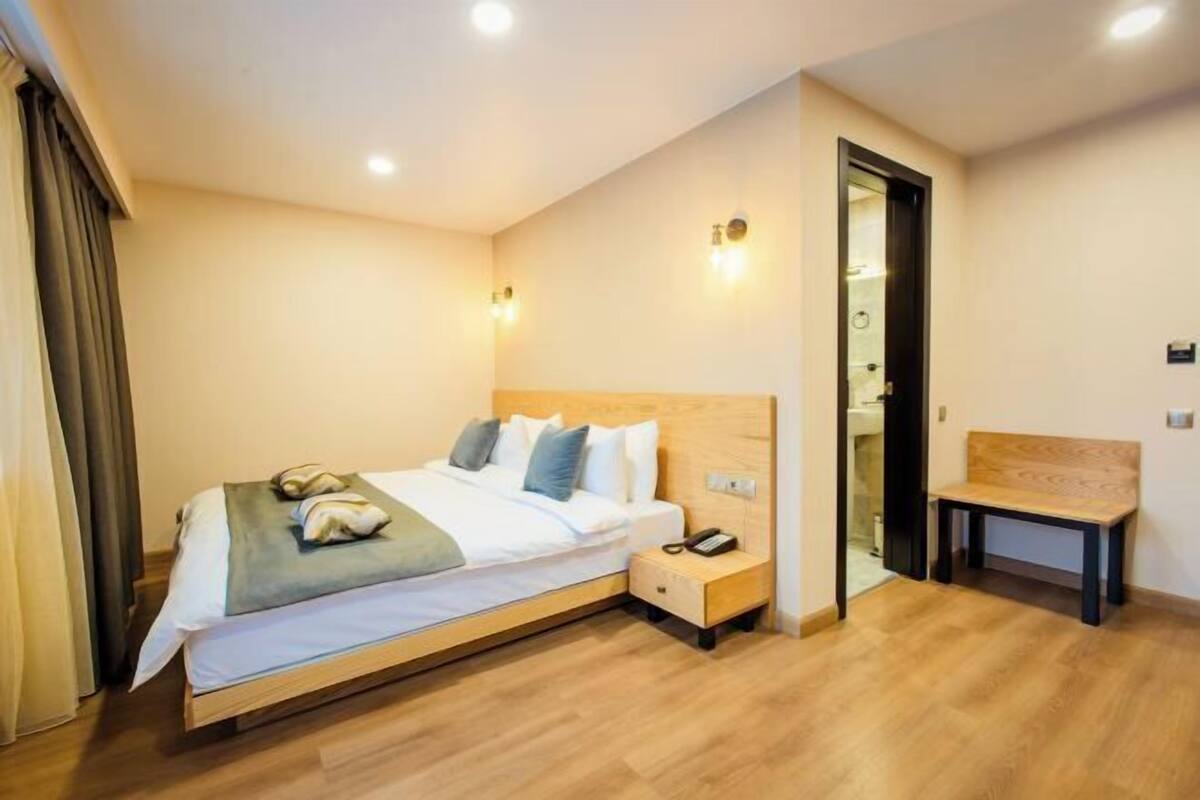 A hotel room with a bed, bedside table, and a bench.