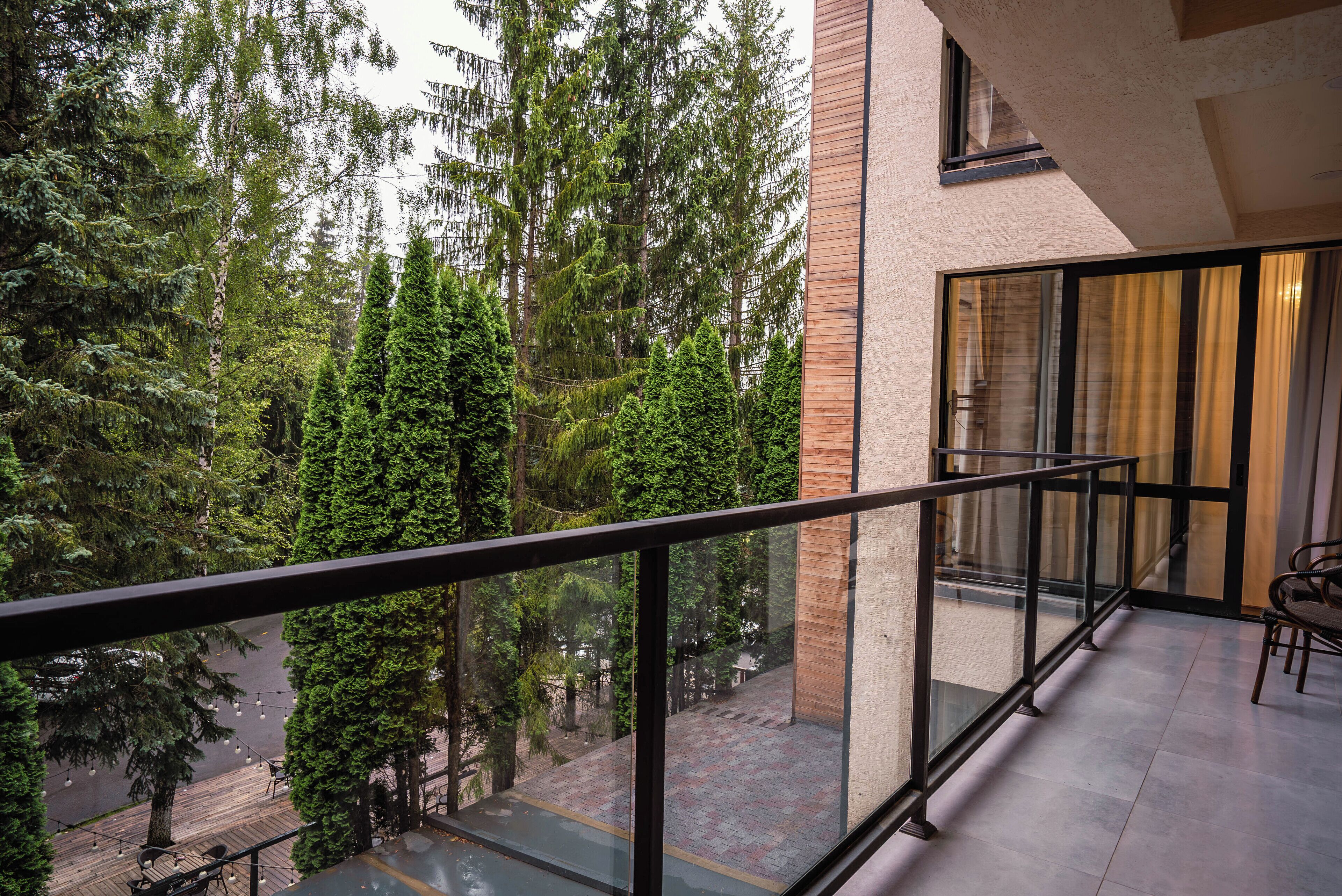 A balcony with a glass railing overlooking a forested area.