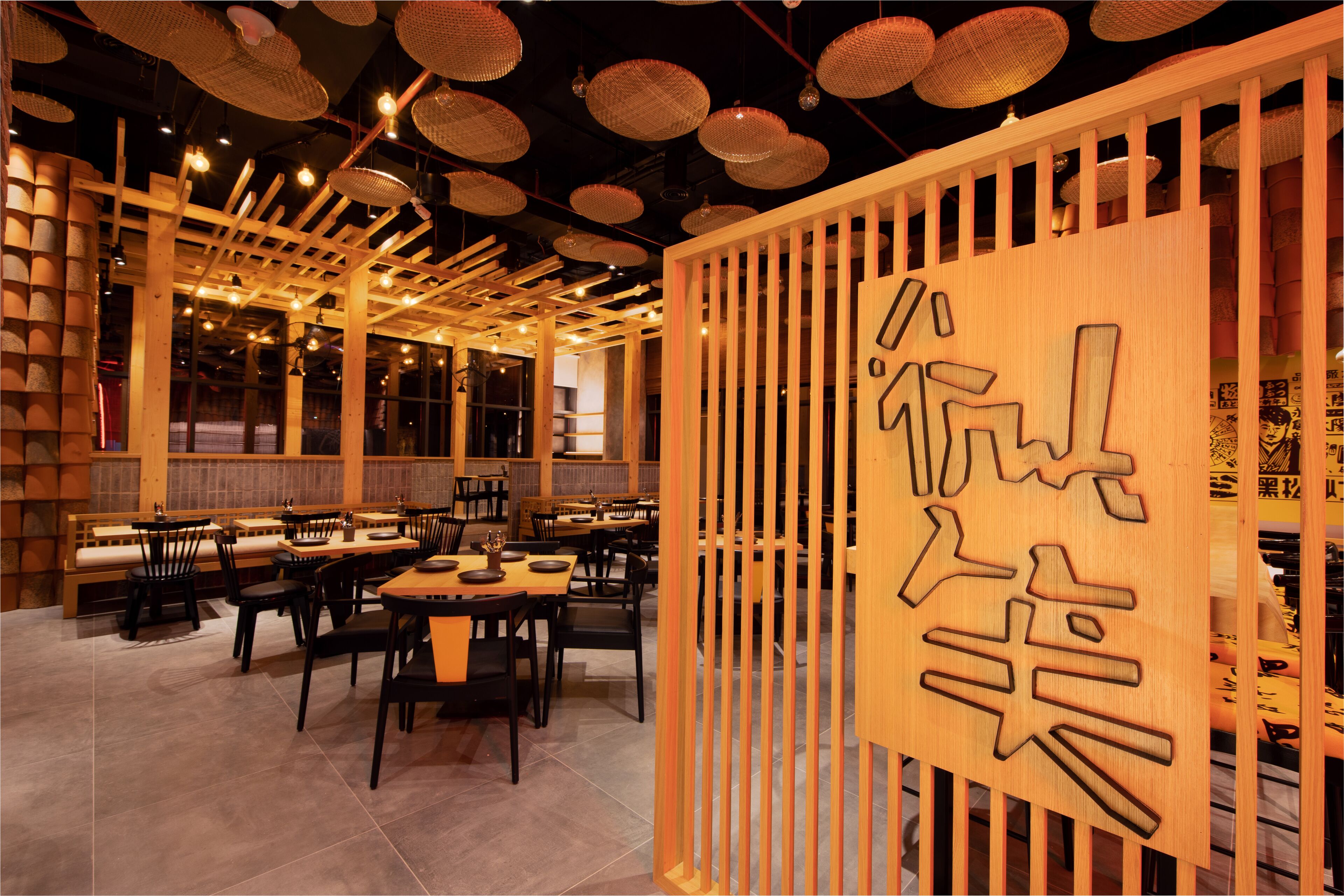 A restaurant interior with wooden furniture, hanging baskets, and a wooden partition with Chinese characters.