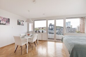 Un dormitorio moderno con un ventanal grande, una cama y un comedor con mesa y sillas.