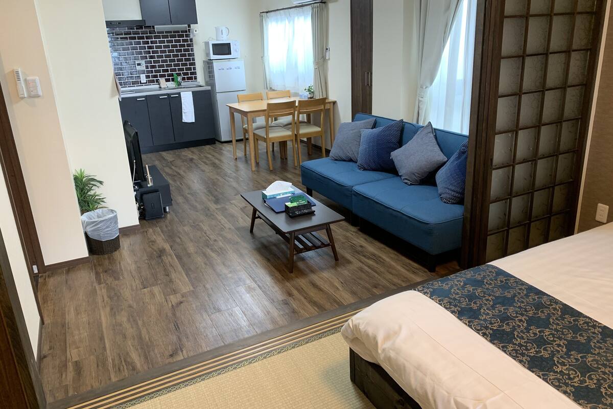 A compact living space with a kitchenette, a sofa, a dining table, and a bed.