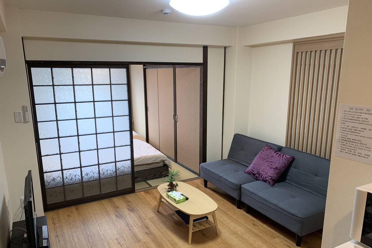 A room with a sliding door, a sofa, a small table, and a television.