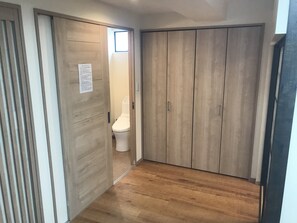Un pasillo con suelo de madera que conduce a una habitación con inodoro y armario.