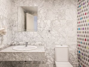 A bathroom with a marble sink, a toilet, and a shower area.