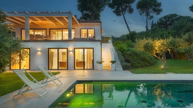 Uma casa moderna de dois andares, com piscina, janelas amplas e um jardim bem cuidado.