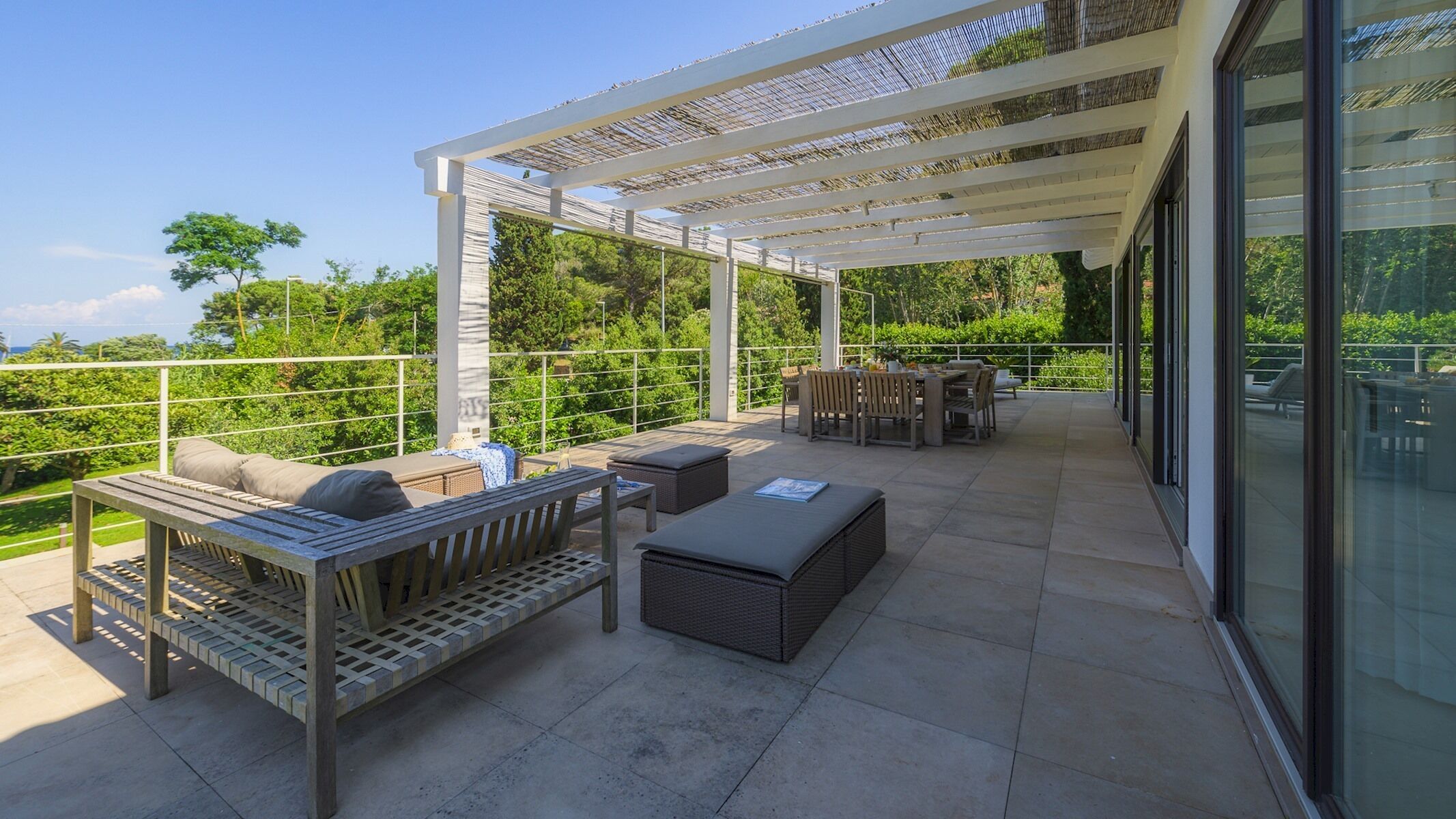 Eine überdachte Terrasse im Freien mit Sitzgelegenheiten, einem Tisch und einer Pergola.