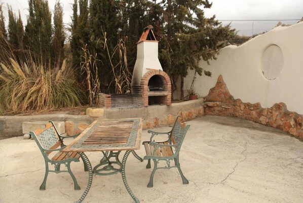 Enjoy dining and socializing in this outdoor patio area with a traditional brick oven and comfortable seating.
