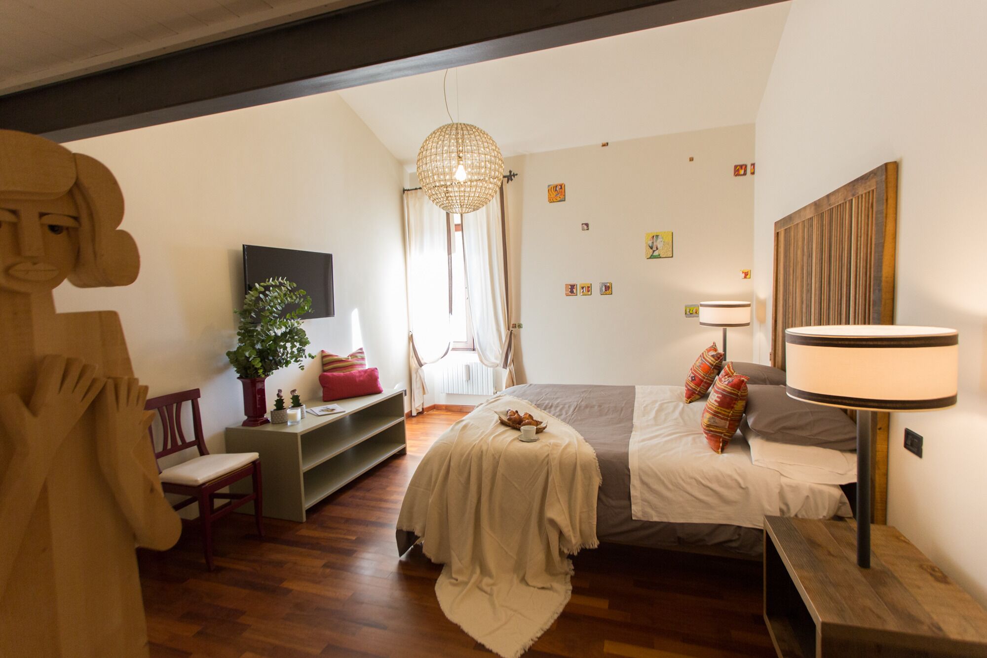 A bedroom with a bed, bedside table, lamp, and a large window.