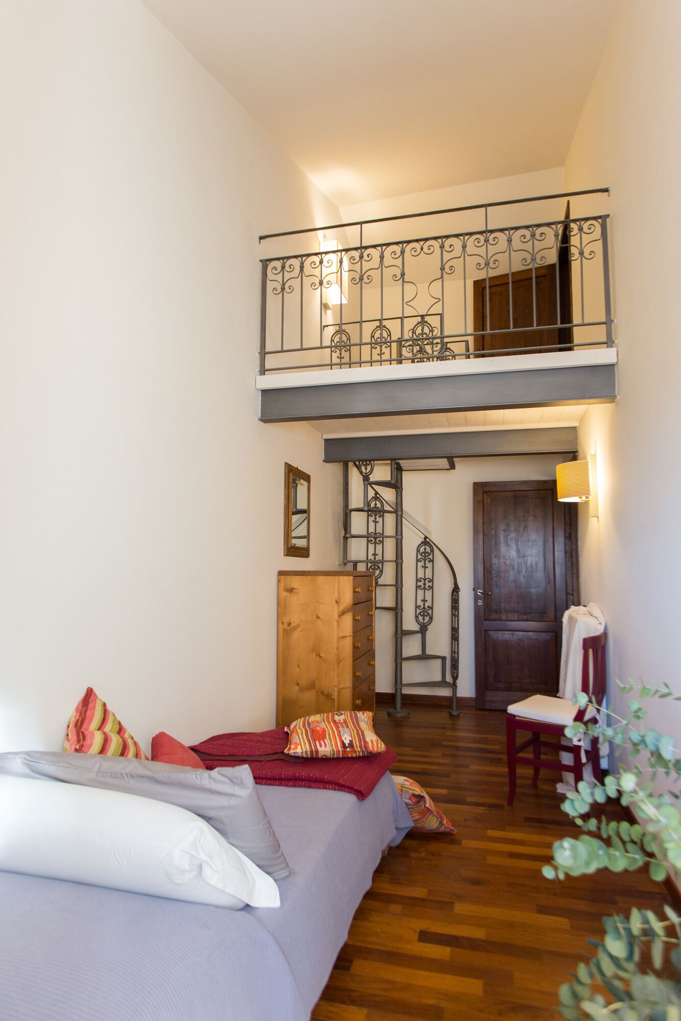 A two-story room with a staircase, a bed, a wooden dresser, and a chair.