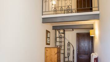 A two-story room with a staircase, a bed, a wooden dresser, and a chair.