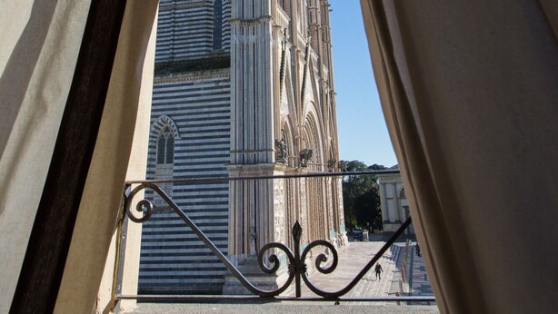 A view of a cathedral through a window with curtains.