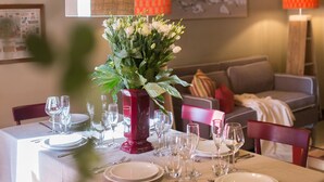 A dining area with a table set for six, a vase of flowers, and hanging woven light fixtures.
