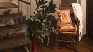 A wooden staircase with a metal railing, a chair with a cushion, and a potted plant.