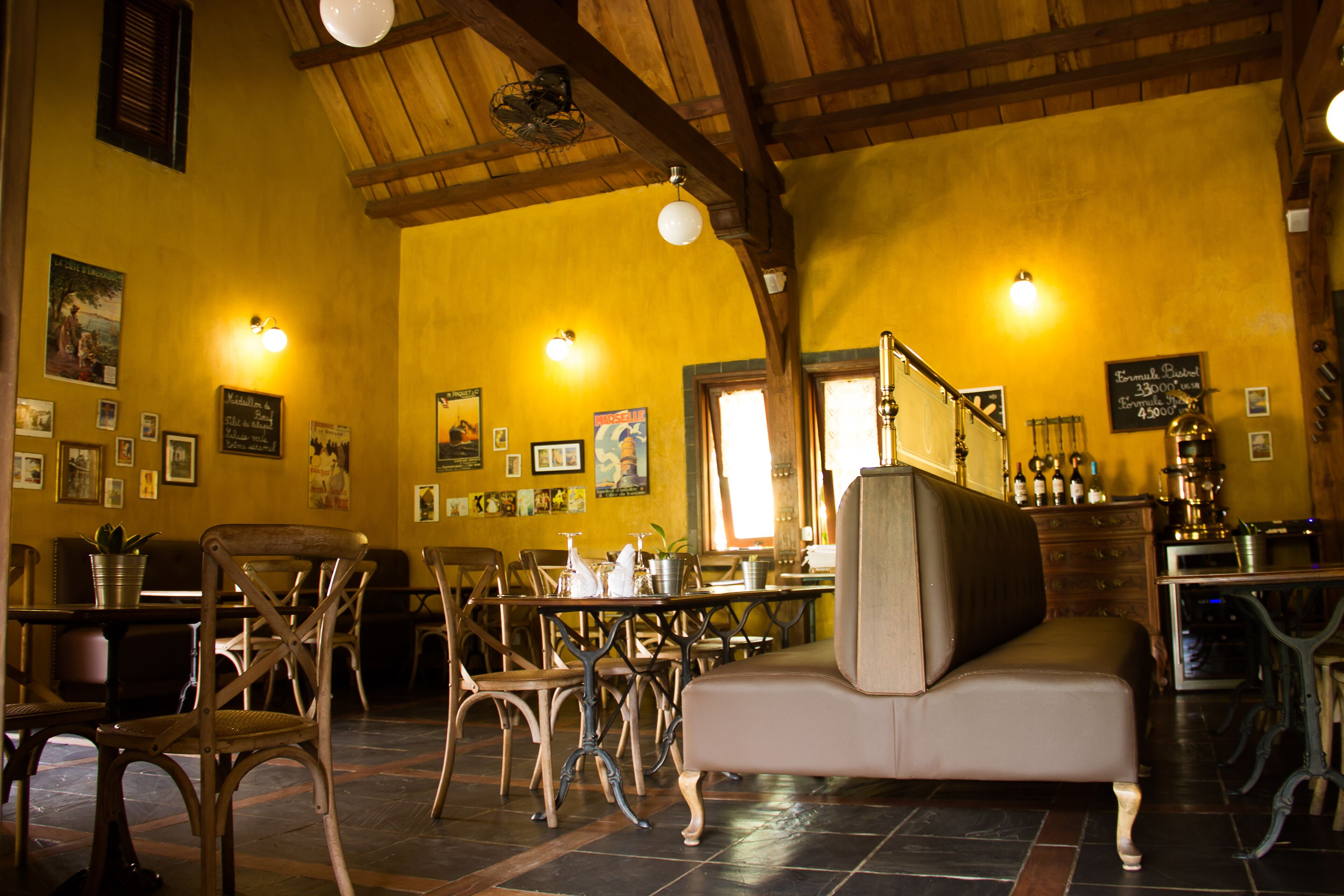 A cozy restaurant interior with wooden furniture, a high ceiling, and warm lighting.
