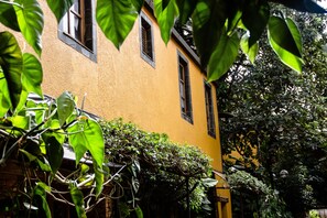 A yellow building with multiple windows and a brick wall. - Hotel Le Bougainviller (Kampala)