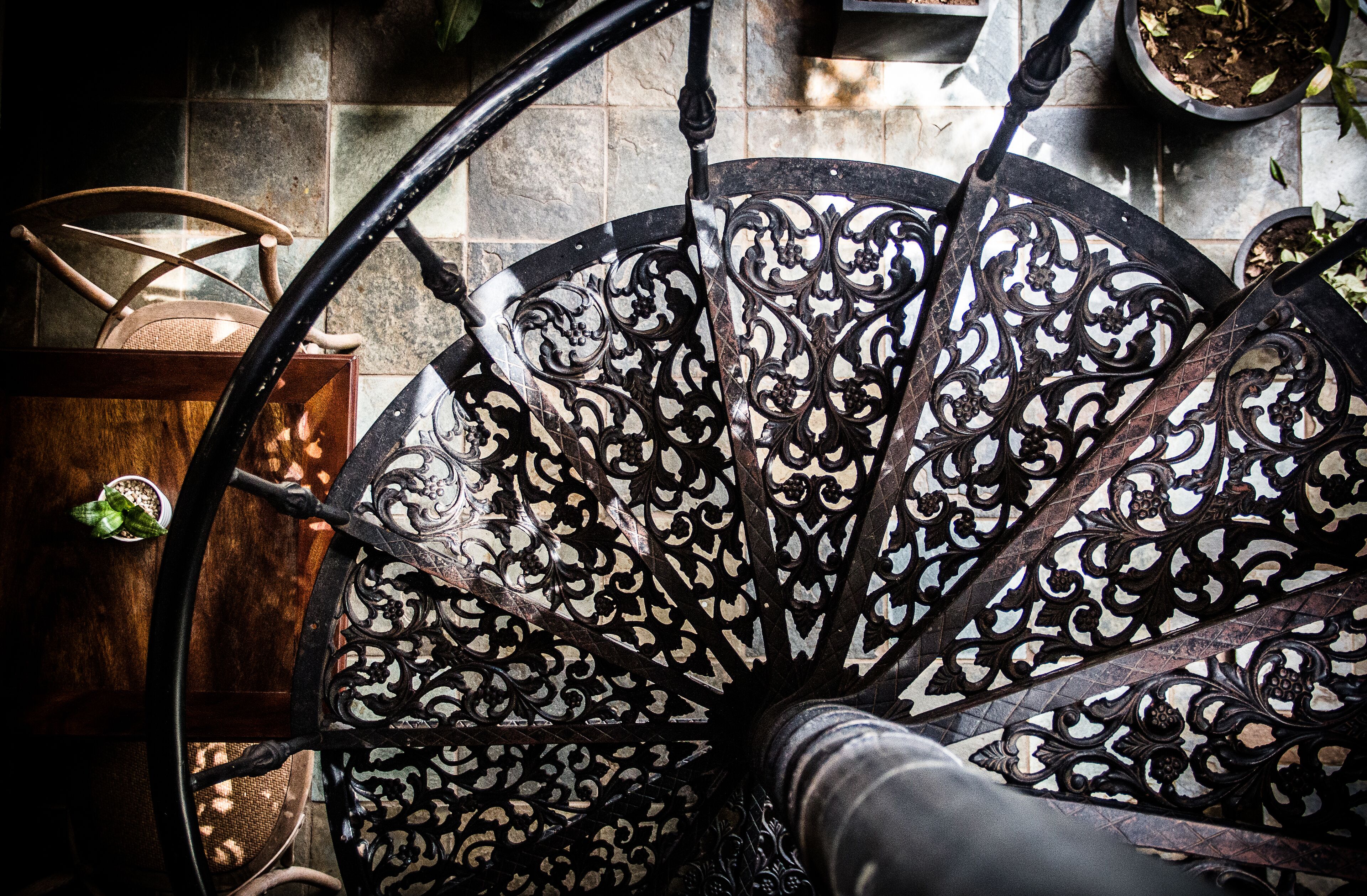 Eine Wendeltreppe mit aufwendiger Metallgalerie und einem Holzstuhl in der Nähe.