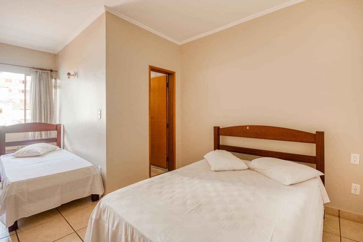 A hotel room with two single beds, a wooden headboard, and a window with curtains.