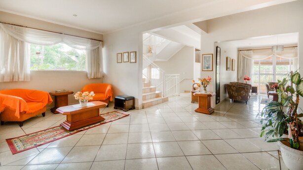 A spacious living room with a staircase, orange sofa, coffee table, and potted plants. - OYO Hotel Vila Rica, Ribeirão Preto (Ribeirão Preto)