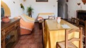 A dining area with a table set for two, a wooden cabinet, and a chair. - La Chumbera Caves - Los Jazmines (Benalua de Guadix)