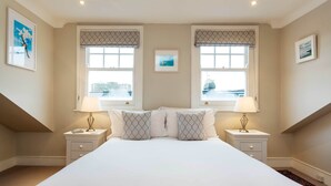 Una camera da letto con un letto grande, due comodini con lampade, una finestra con vista e un quadro appeso al muro.