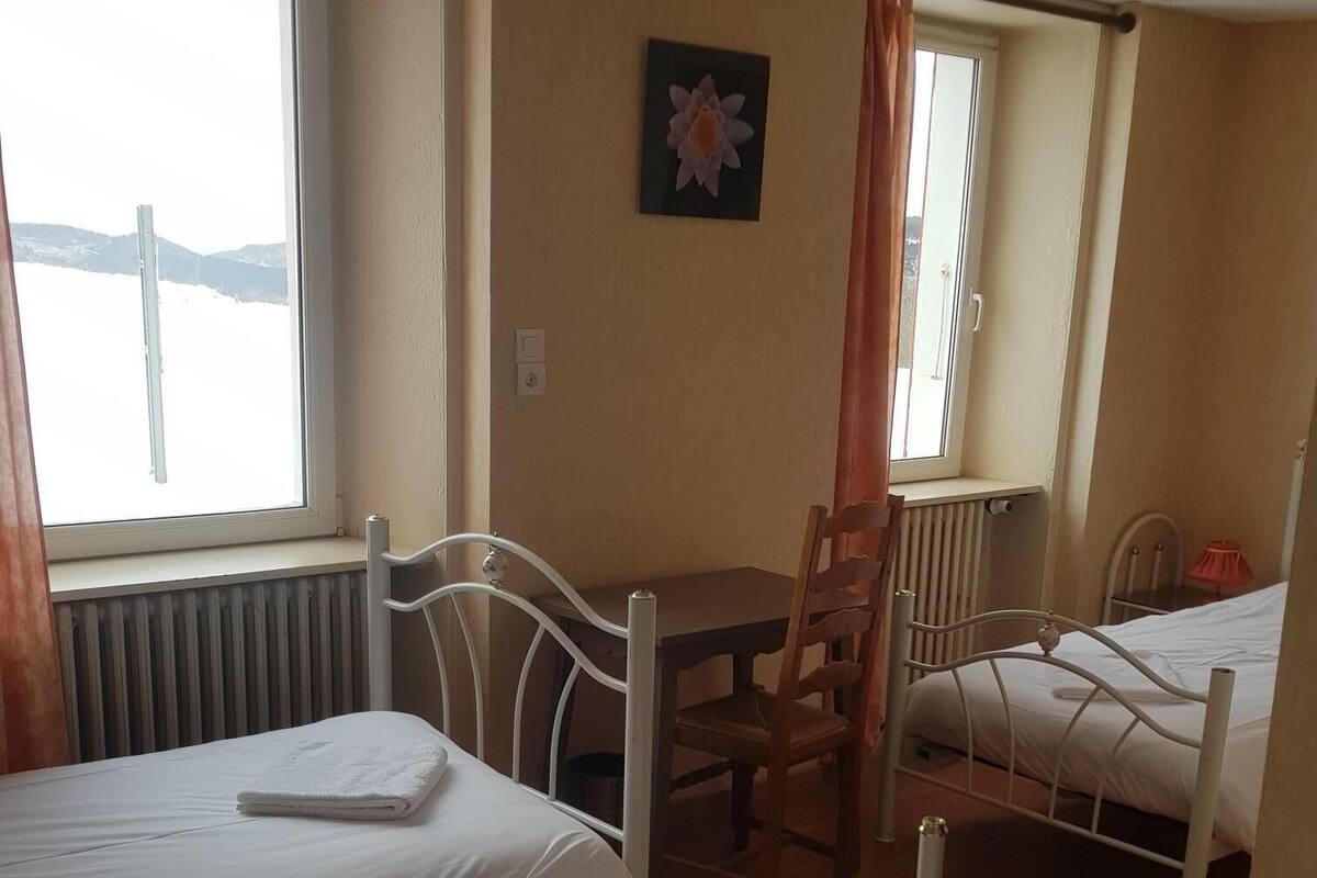 A room with two beds, a table, and a chair.
