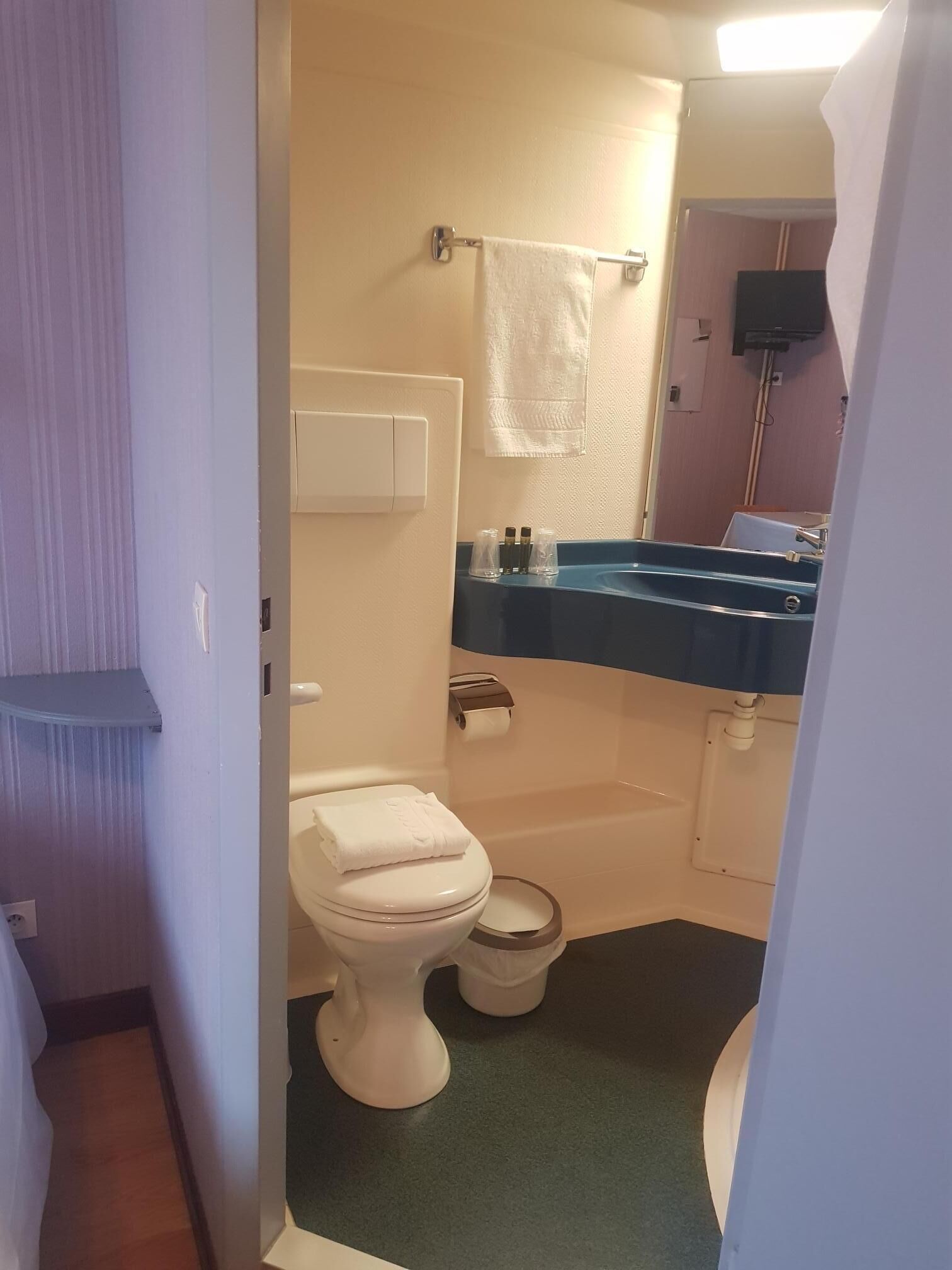 Un baño pequeño con inodoro, lavamanos y espejo.