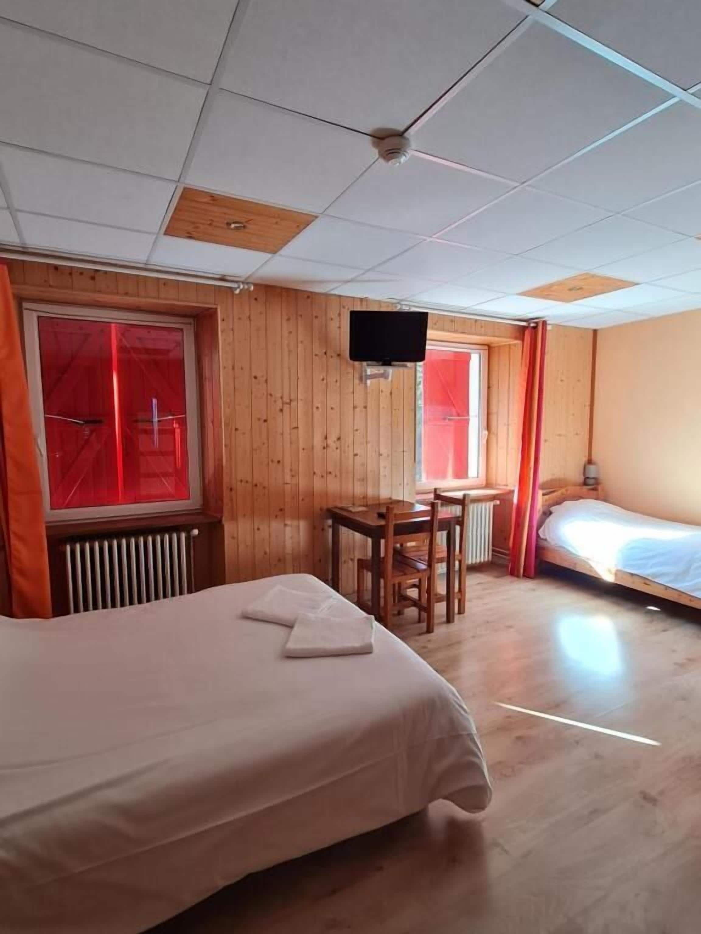 A room with two beds, a desk, and a television.