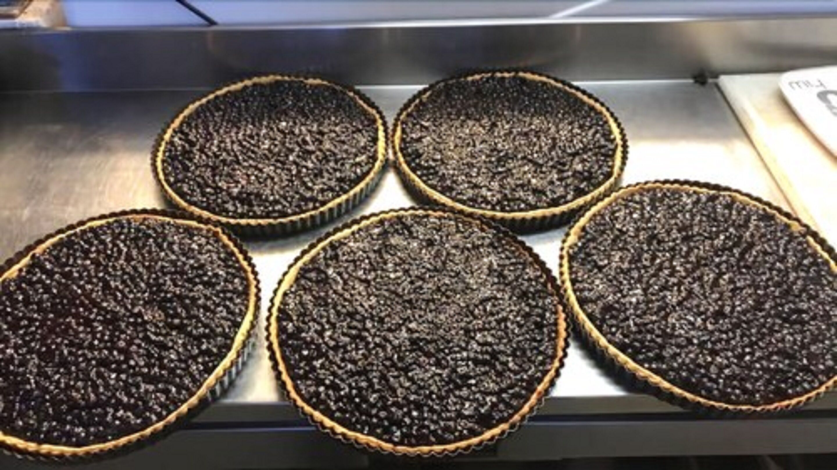 Four round pies with a textured surface, placed on a metal surface.