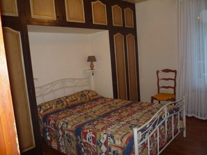 A bedroom with a bed, a chair, and a window with curtains.