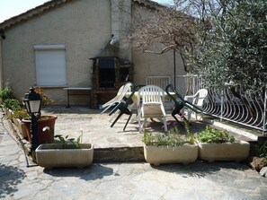 A patio area with outdoor furniture, potted plants, and a building with a tiled roof.