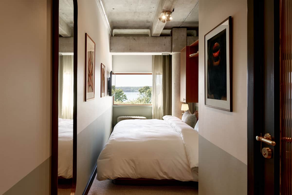Une chambre d’hôtel avec un grand lit, une fenêtre donnant sur un beau paysage et une porte qui mène à une autre pièce.