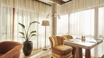 Un comedor con una mesa dispuesta para cuatro personas, una planta en maceta y una lámpara de pie alta.