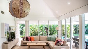 Ein modernes Wohnzimmer mit einer großen Eckcouch, einem Couchtisch und einer Pendelleuchte.